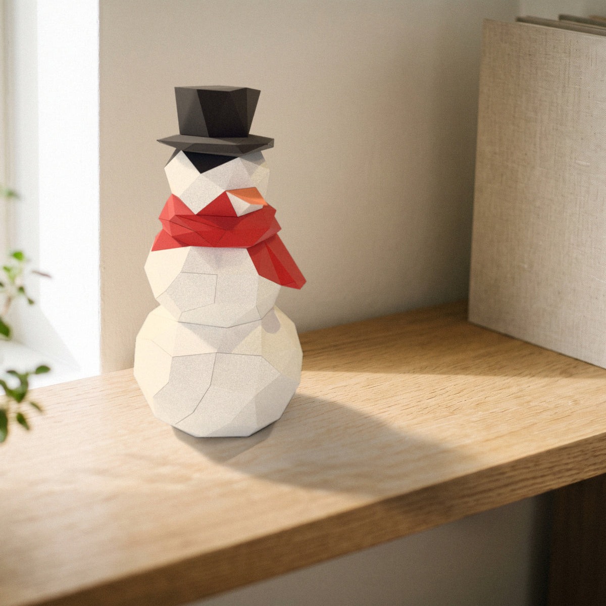Paper Snowman model on a bookshelf